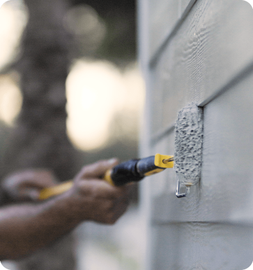 paint contractor painting outside of house with roller