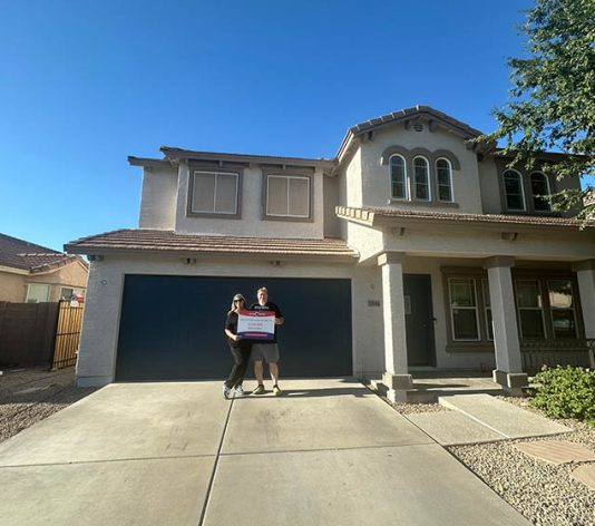 homeowners smiling in front of their new painted house